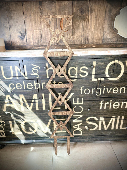 Walnut Colossal Inverted Triangle indoor plant trellis displayed upright against a rustic painted wood cabinet