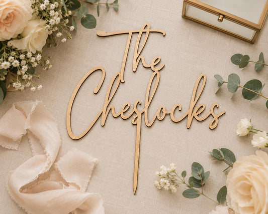 Personalized script wood cake topper in a dark finish on a wedding cake as the couple cuts the cake