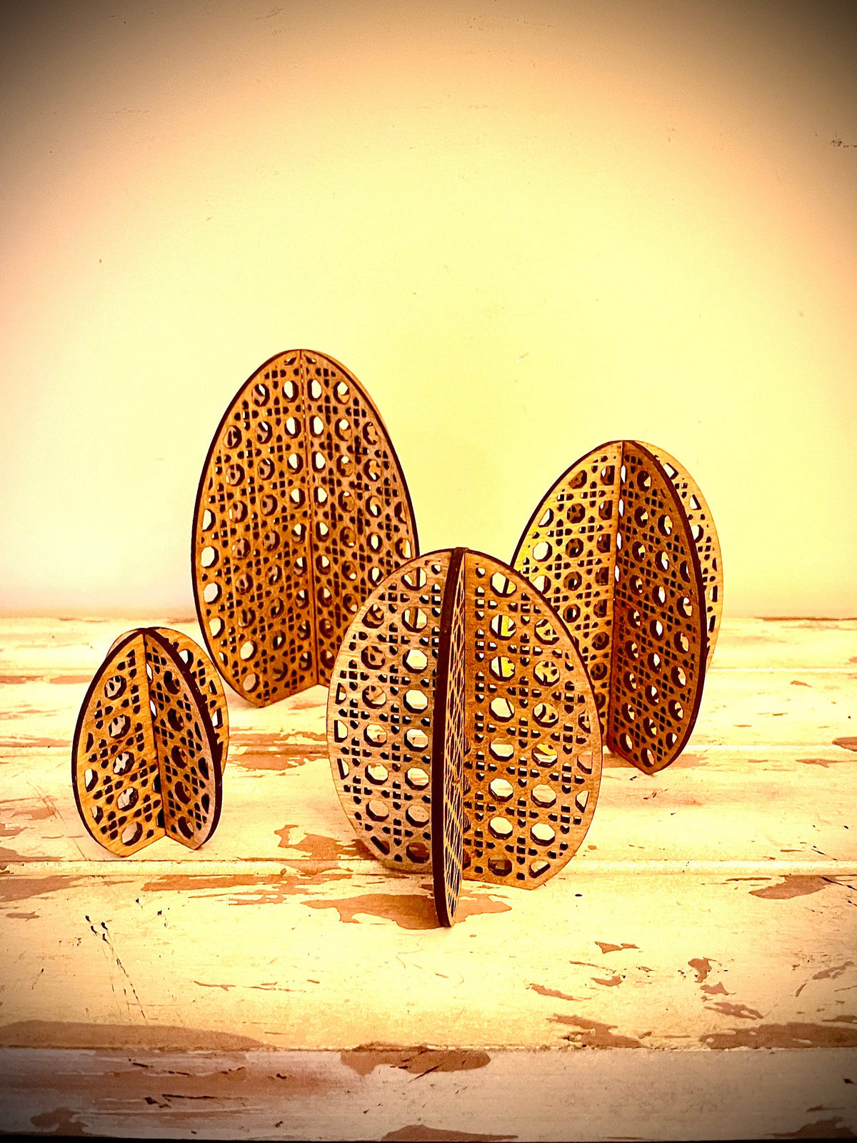 A set of boho rattan-style laser-cut wood Easter eggs in graduated sizes standing as tabletop spring decor.