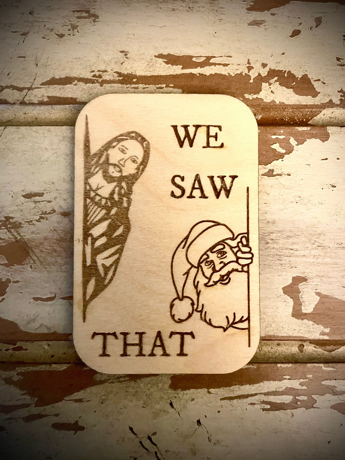 A funny wood refrigerator magnet showing Santa and Jesus with the caption "We Saw That" engraved below.