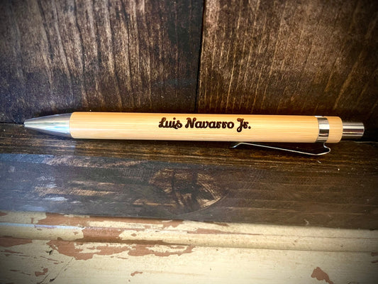 Engraved wood writing pen with a name engraved on the barrel, lying on a wooden surface