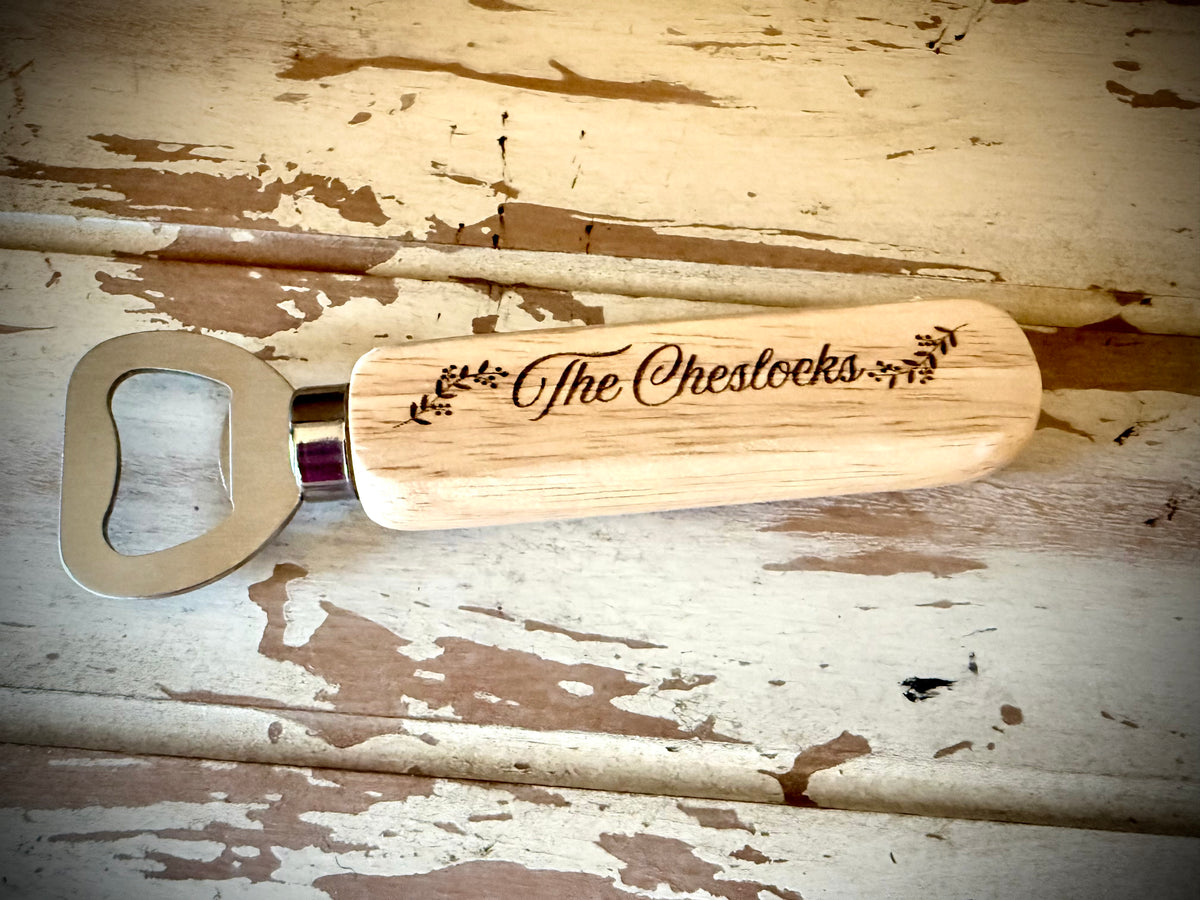 Personalized wooden wedding favor bottle opener engraved with last name displayed on a distressed white wood surface