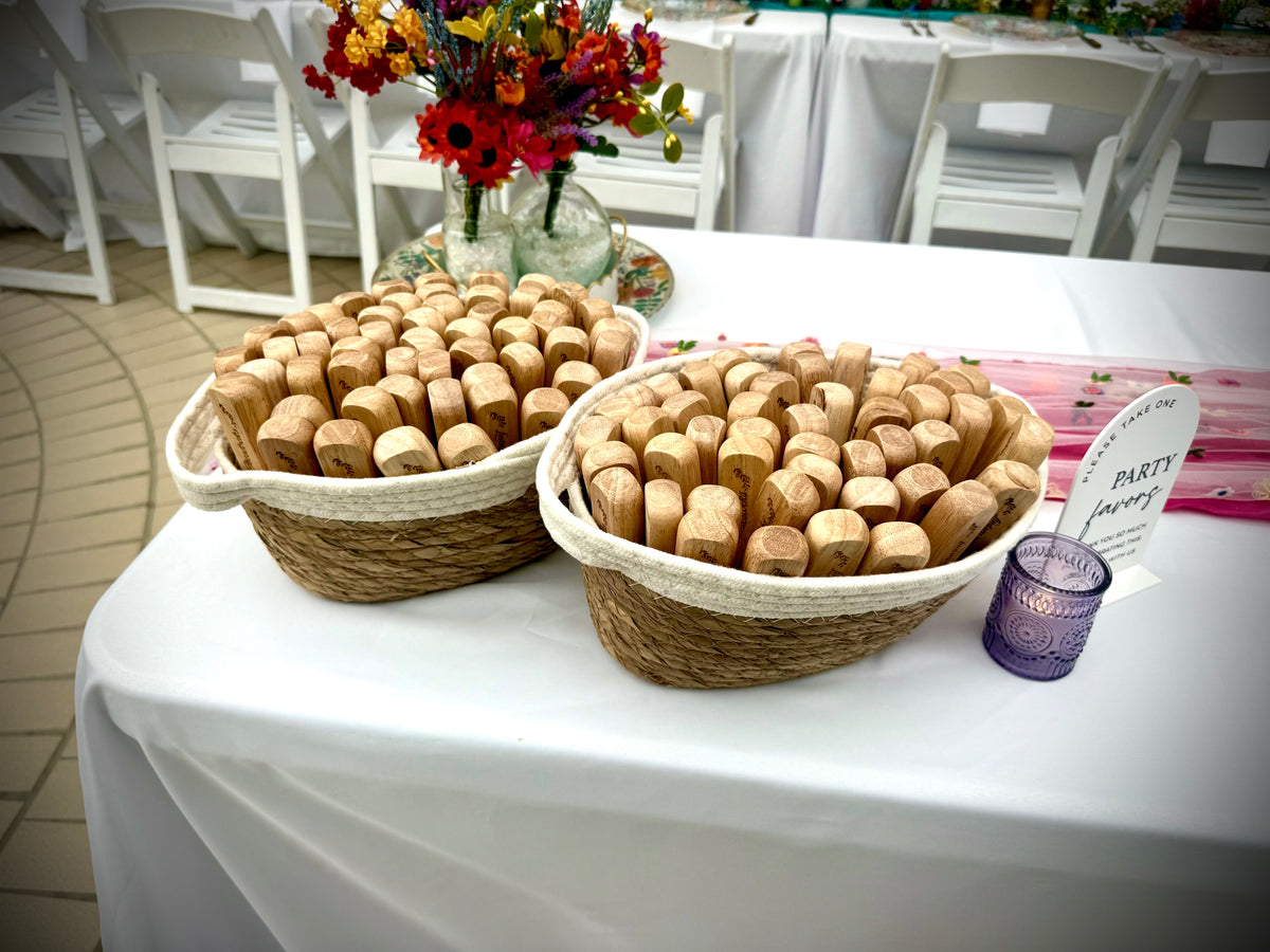 Baskets filled with personalized wooden bottle opener wedding favors displayed beside flowers on a reception table