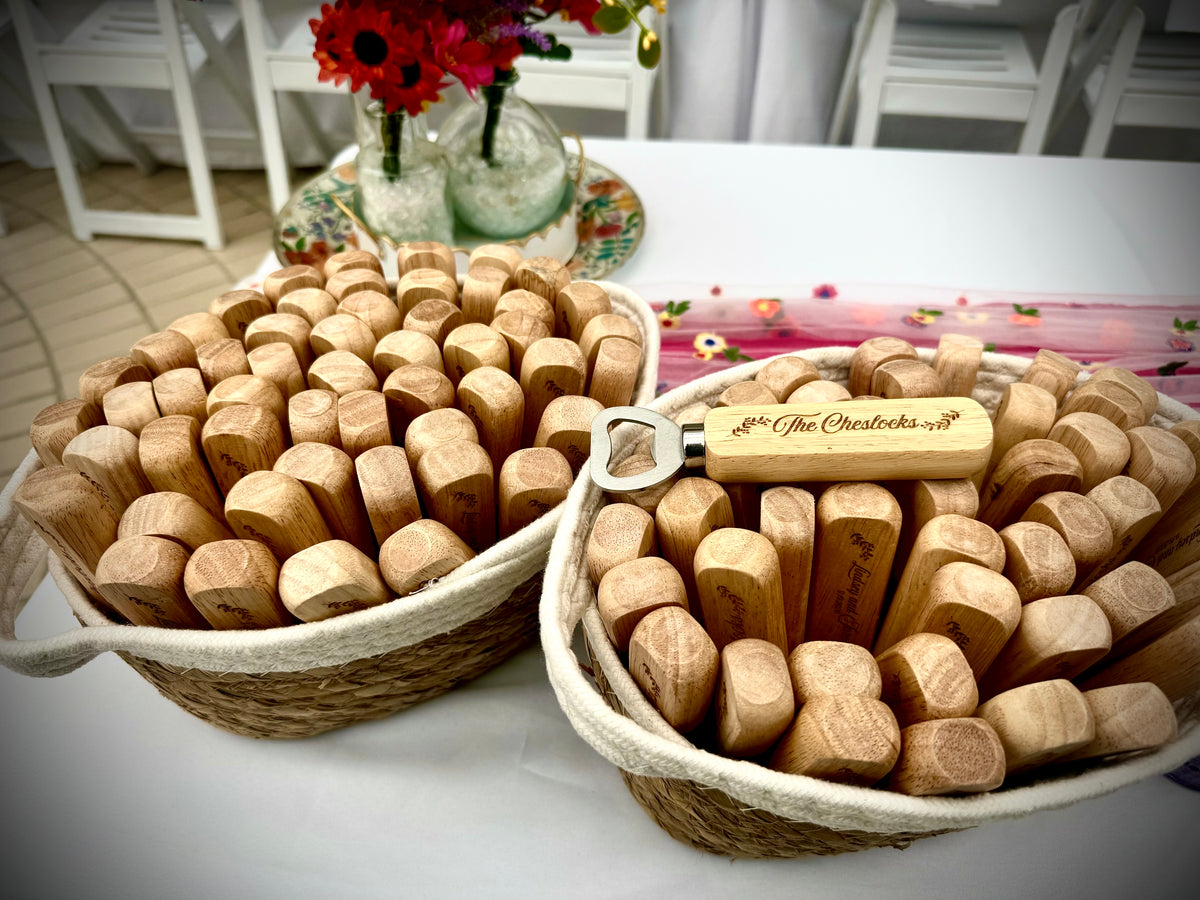 Baskets of personalized wooden bottle opener wedding favors displayed on a reception table, with one opener engraved with last name