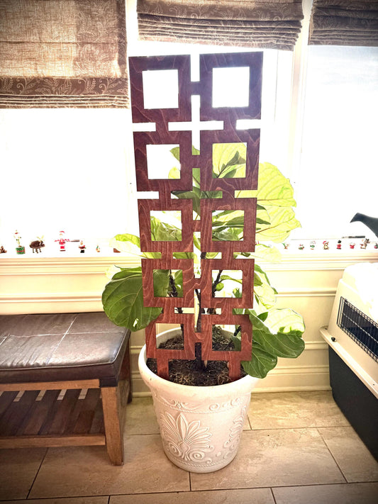 Dark wood Colossal Square Shapes indoor plant trellis supporting a large leafy houseplant in a white decorative pot beside a bright window