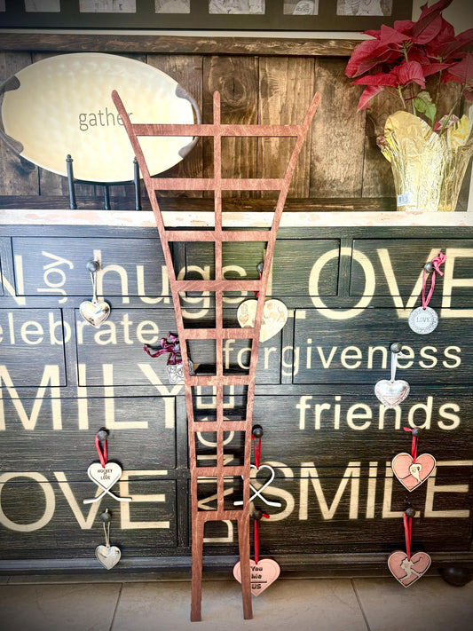 Tall traditional wooden plant trellis displayed in front of a rustic farmhouse-style chest, with hanging heart ornaments and a potted red-leaf plant