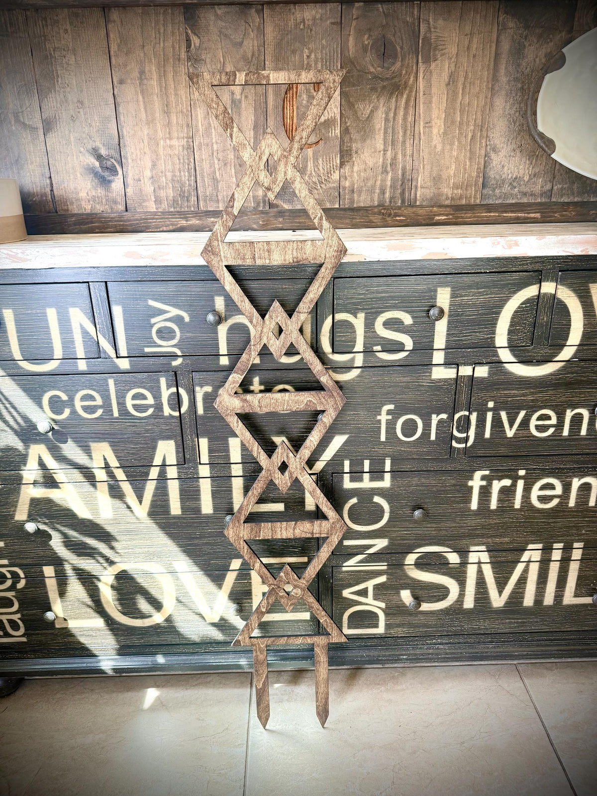 Walnut Colossal Inverted Triangle indoor plant trellis displayed upright against a rustic painted wood cabinet