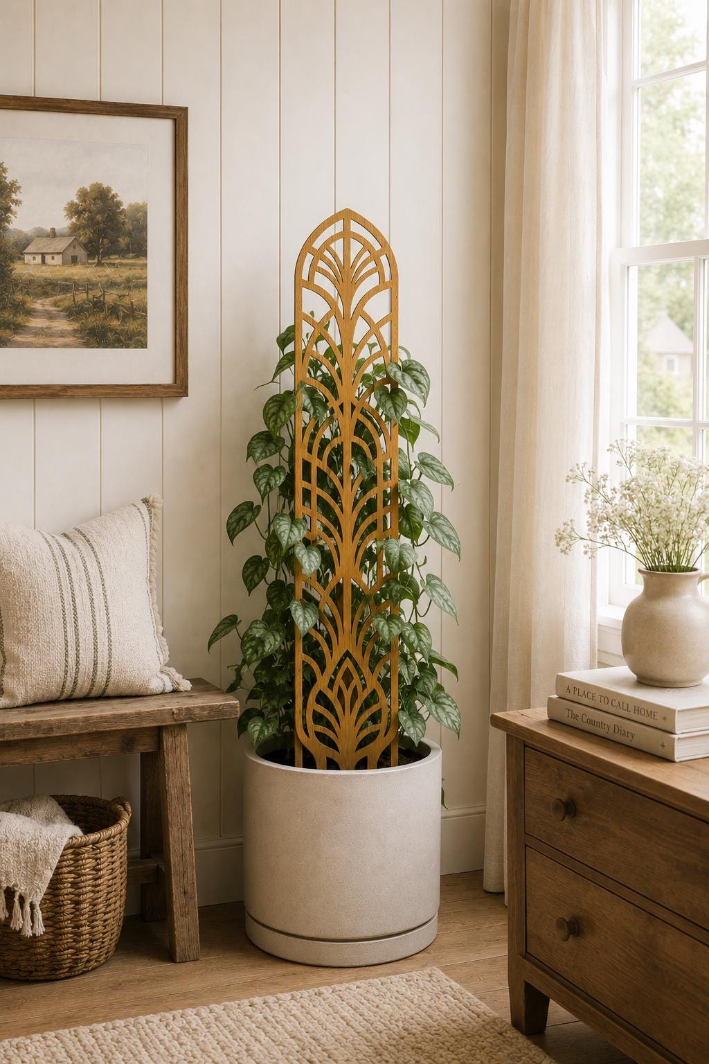Colloquial arch plant trellis supporting a leafy climbing houseplant in a white planter in a bright cottage-style room, beside a wooden bench and window.