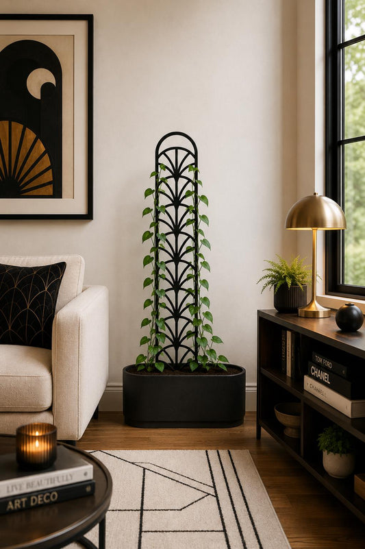 Colossal Art Deco Fan Trellis supporting a climbing houseplant in a black planter beside a bright window in a modern living room.
