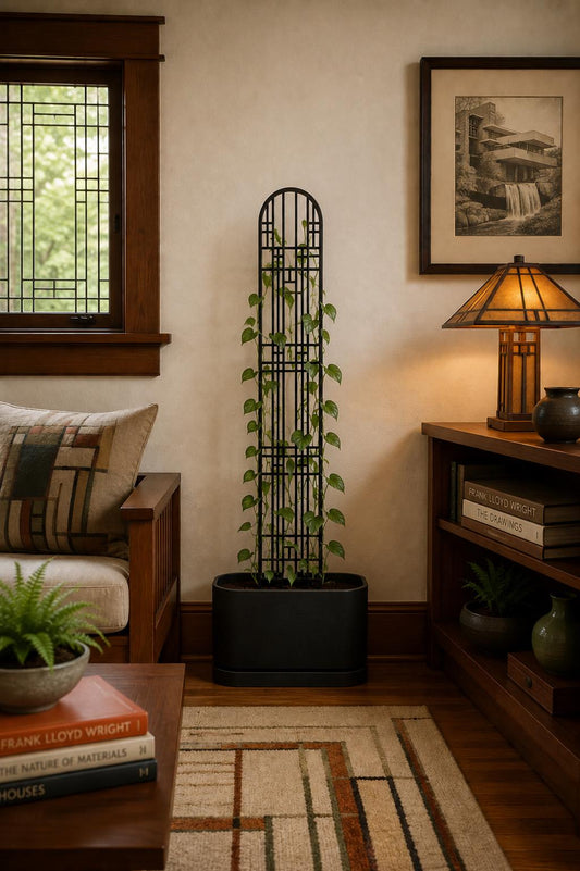 Art Deco geometric plant trellis supporting a climbing houseplant in a black planter beside a window in a warmly furnished living room.