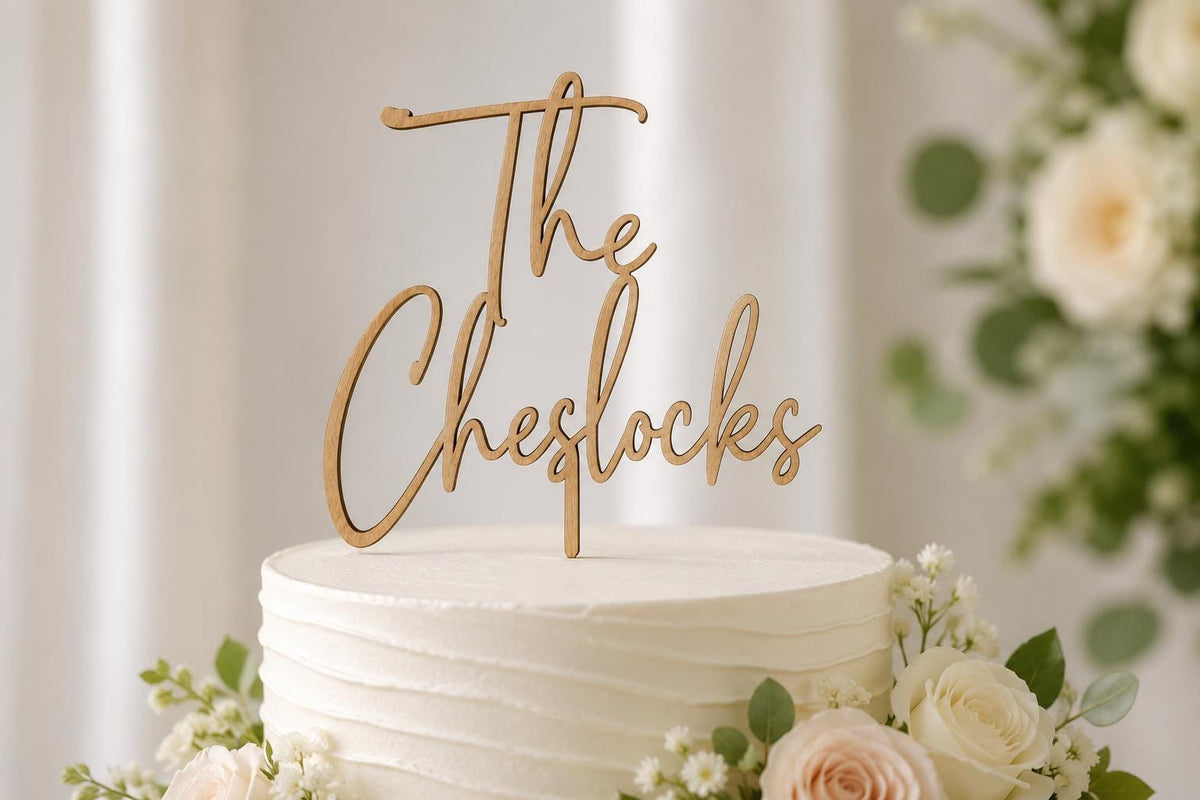 Personalized wood wedding cake topper with script last name on a white wedding cake with white flowers