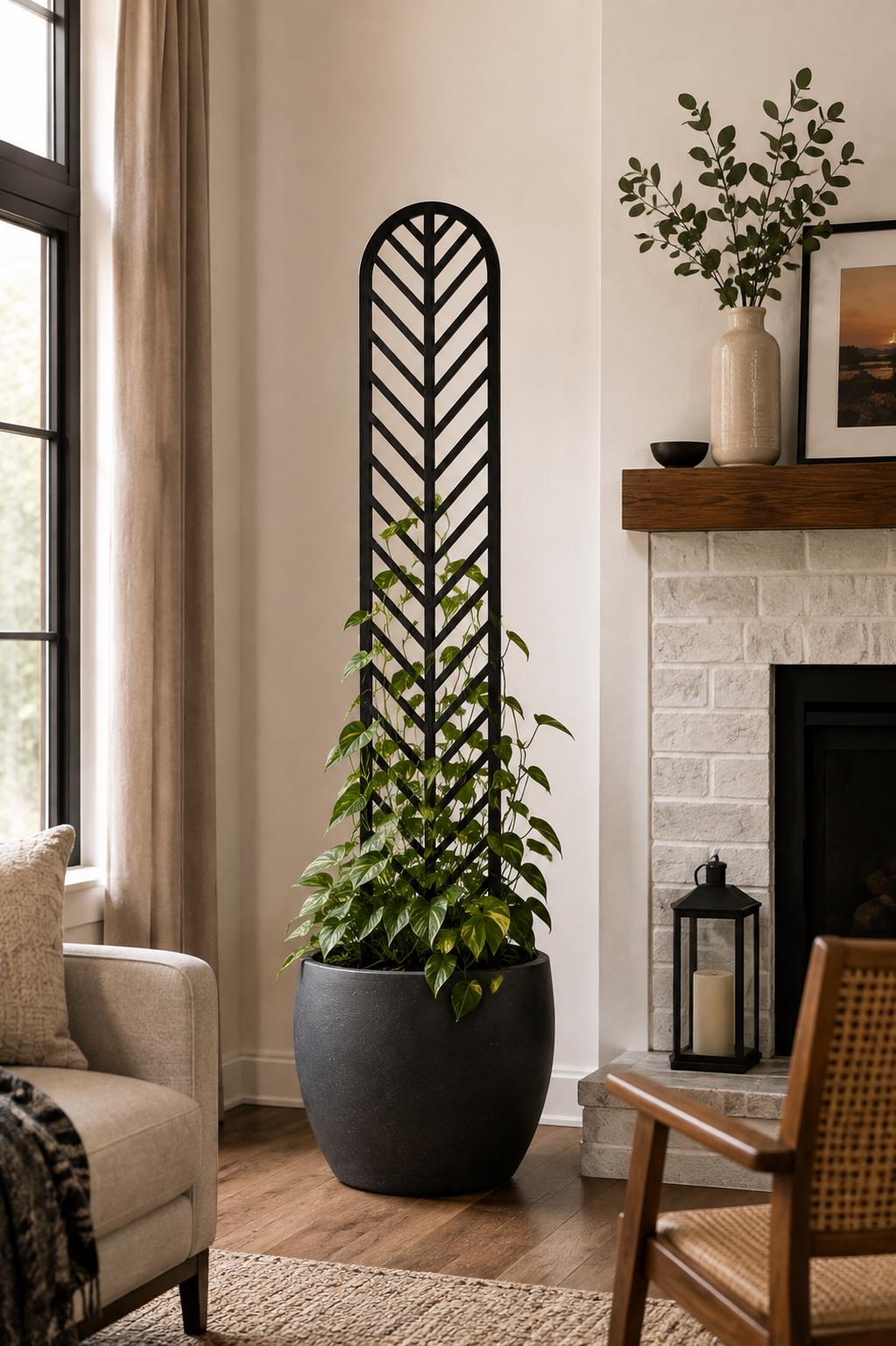 Colossal Herringbone plant trellis in ebony finish with a climbing pothos in a dark round pot, displayed in a modern living room beside a white brick fireplace