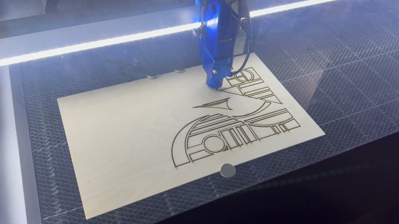 The OMTech laser cutting a wood design in the Downsized Designs workshop in Carmel, Indiana